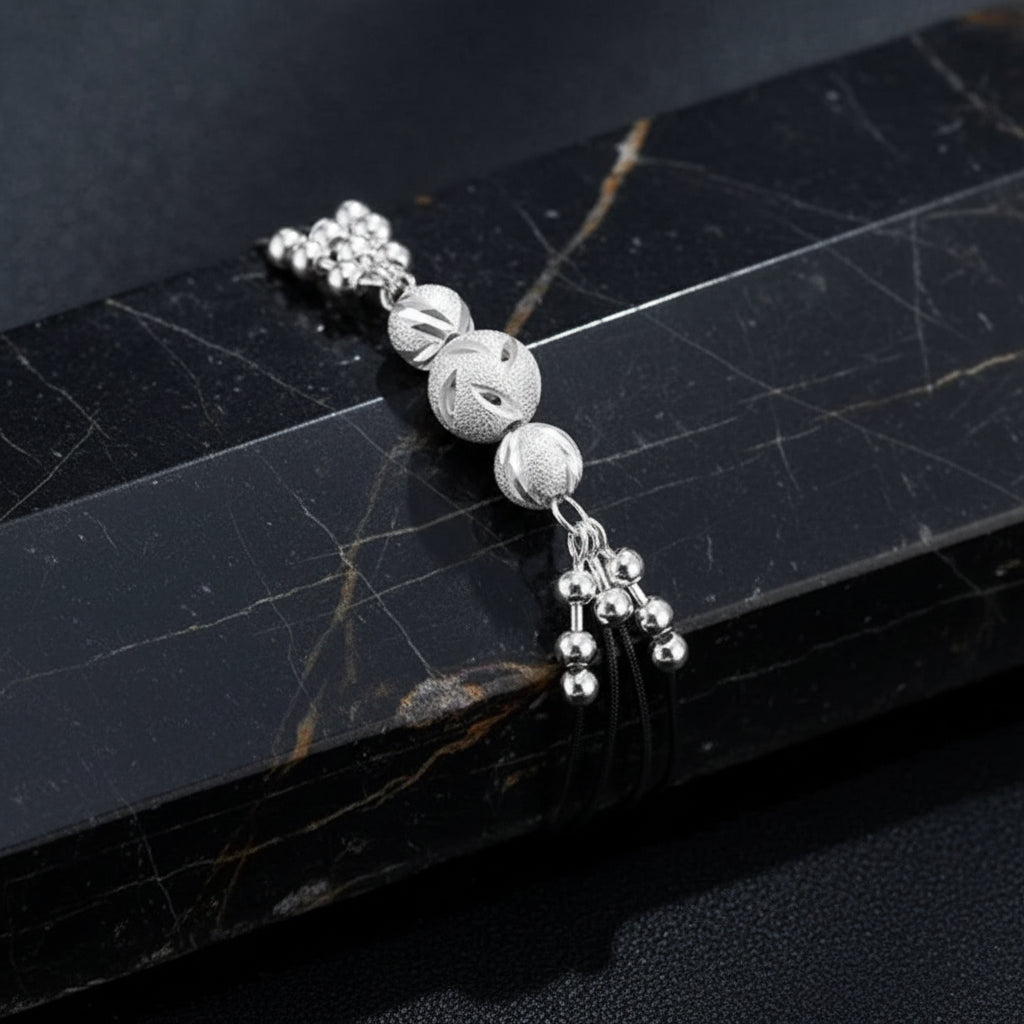 Silver beaded bracelet on a dark blue textured background