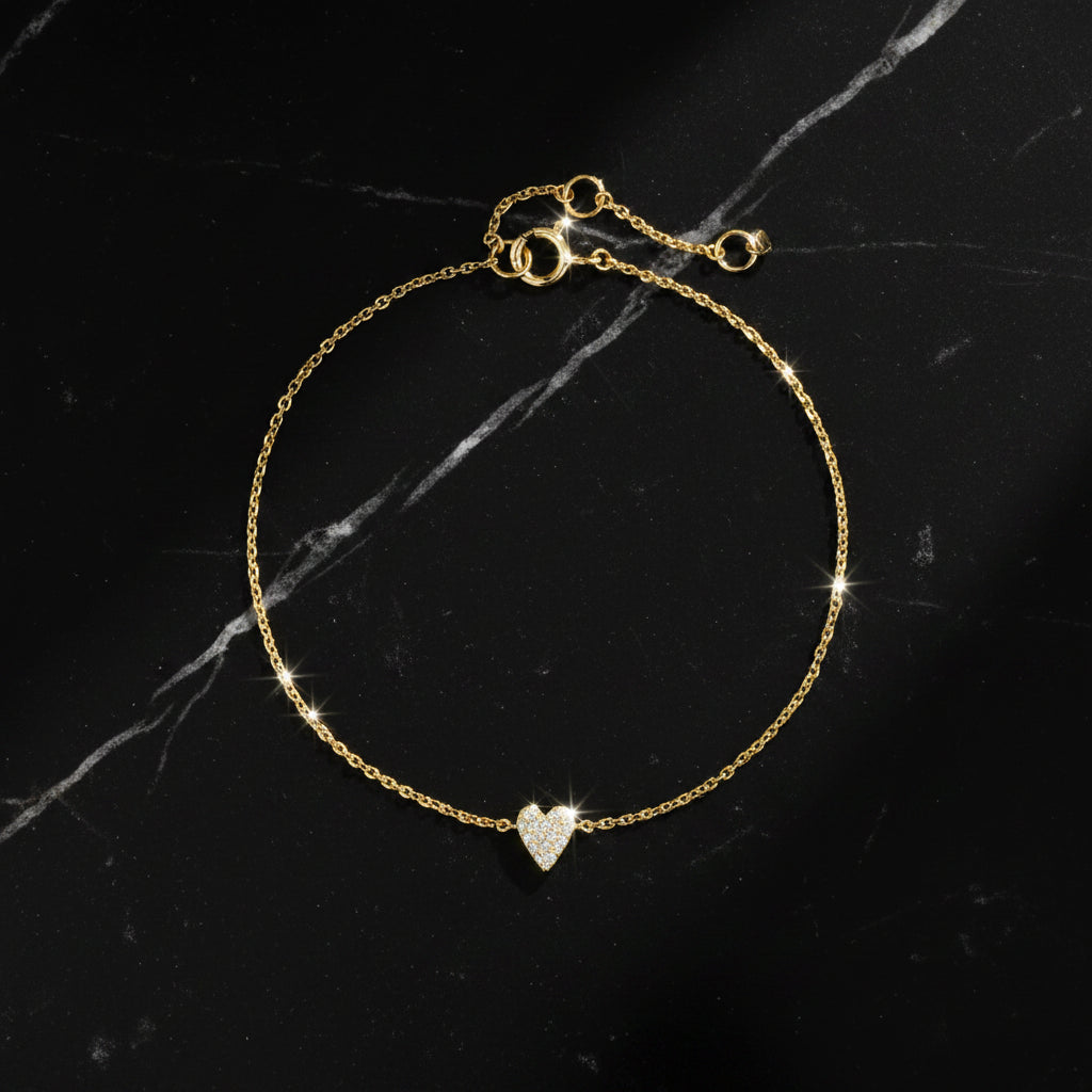 A delicate gold chain bracelet with a small pave-set heart charm, displayed on a clean white background with the brand name DPLAOPA in the top left corner.